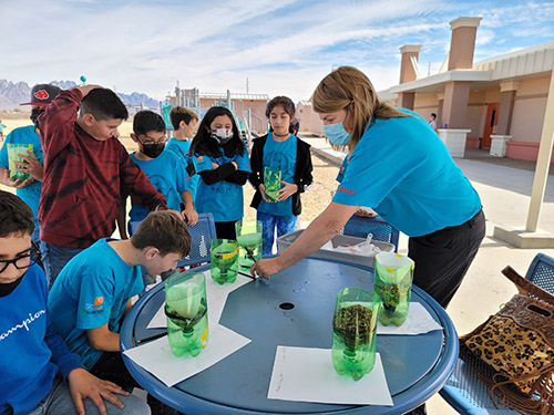 adult woman helping a group of students with a project outside